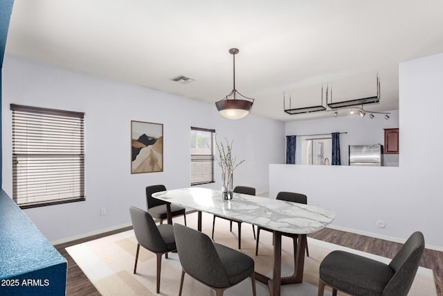 dining area featuring visible vents, baseboards, and wood finished floors