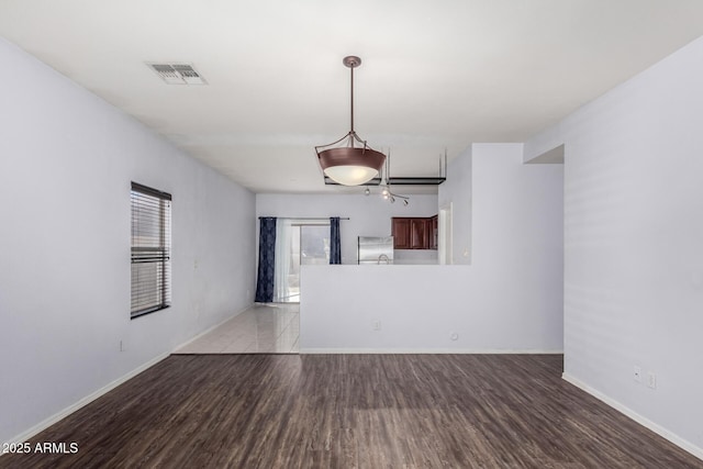 unfurnished room featuring light wood finished floors, visible vents, and baseboards