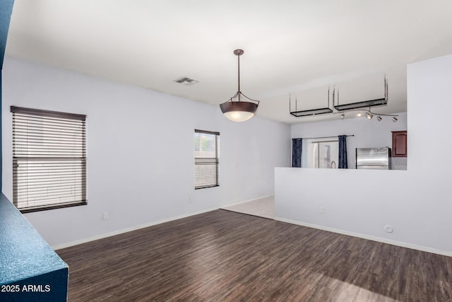 spare room with visible vents, baseboards, and wood finished floors