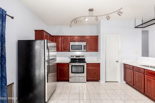 kitchen with dark brown cabinets, light countertops, appliances with stainless steel finishes, light tile patterned flooring, and a sink