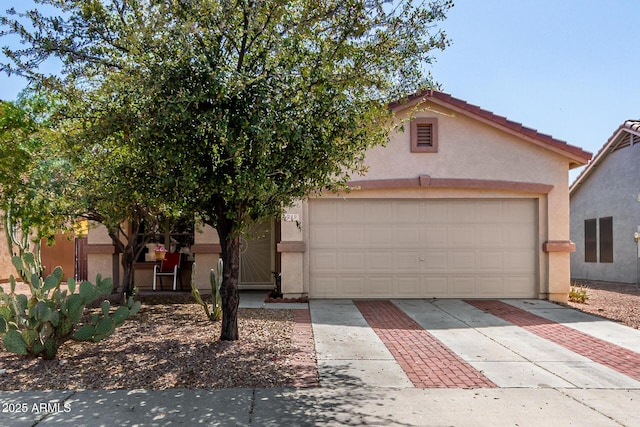 view of front facade with concrete driveway, an attached garage, a tile roof, and stucco siding