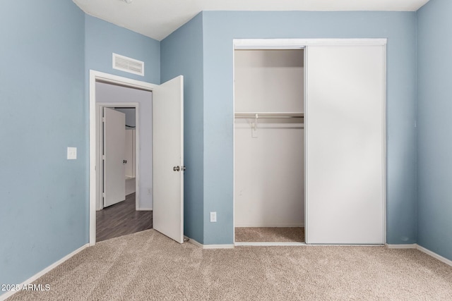 unfurnished bedroom featuring baseboards, visible vents, carpet floors, and a closet