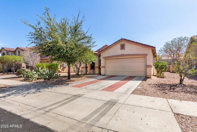 view of front of house with stucco siding, an attached garage, driveway, and a tiled roof