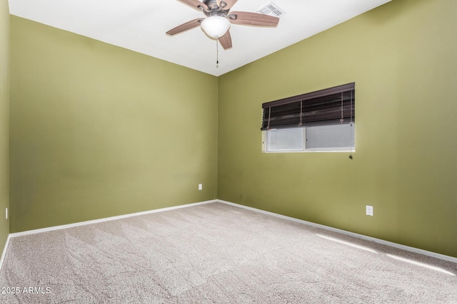 empty room with carpet flooring, a ceiling fan, visible vents, and baseboards