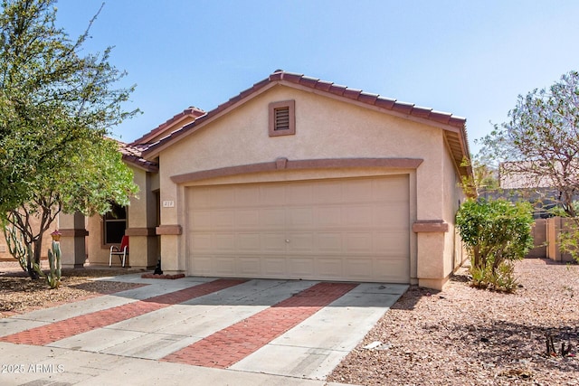 view of front of property with stucco siding, concrete driveway, an attached garage, and a tiled roof