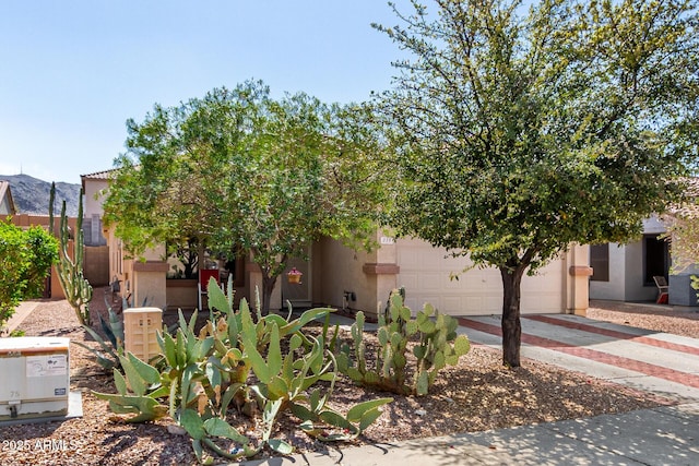 view of front of property with fence, a garage, driveway, and stucco siding