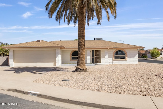 single story home with concrete driveway, brick siding, an attached garage, and a shingled roof