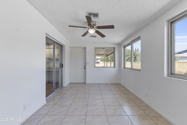 empty room featuring light tile patterned floors, ceiling fan, visible vents, and a textured ceiling