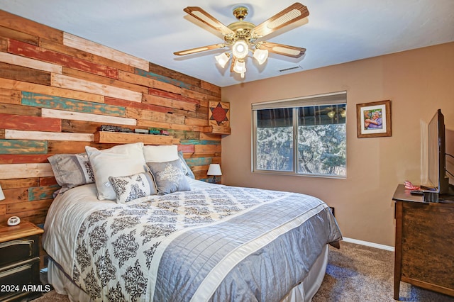 bedroom with ceiling fan, wood walls, and dark colored carpet