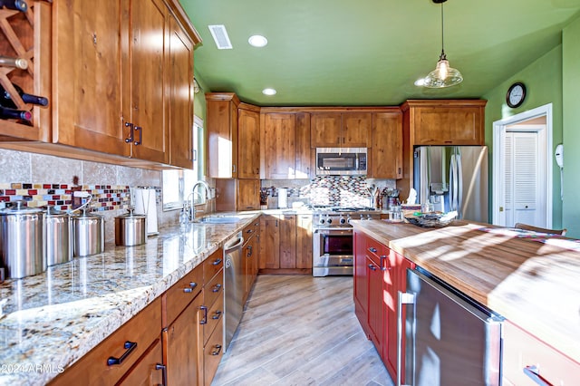 kitchen featuring pendant lighting, wooden counters, beverage cooler, stainless steel appliances, and light hardwood / wood-style flooring