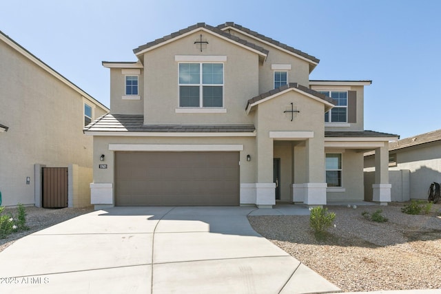 traditional home featuring a garage, a tiled roof, concrete driveway, and stucco siding