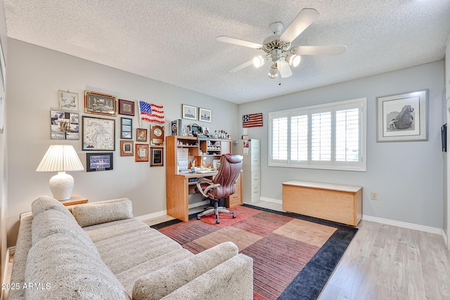 home office with water heater, a ceiling fan, a textured ceiling, wood finished floors, and baseboards