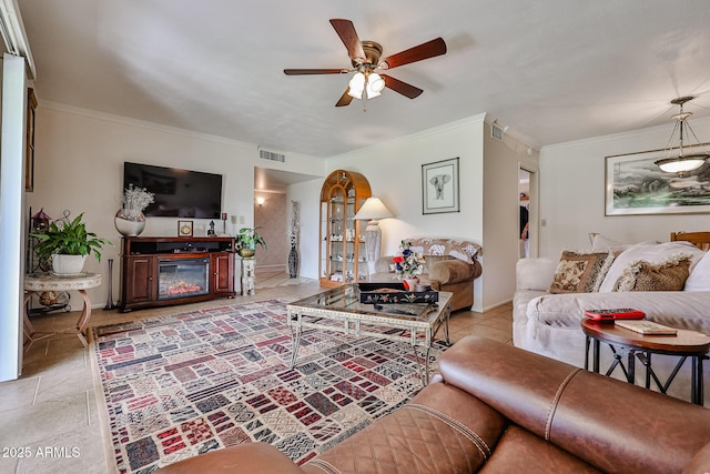 living area with visible vents, a glass covered fireplace, a ceiling fan, and ornamental molding