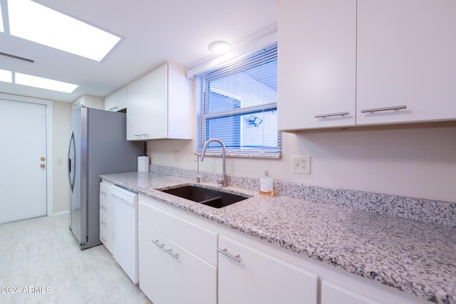 kitchen featuring light stone countertops, sink, white dishwasher, white cabinets, and light wood-type flooring