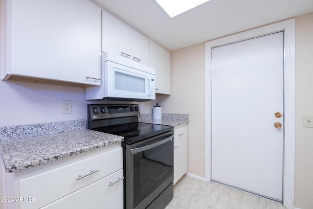 kitchen featuring light stone countertops, white cabinetry, and black range with electric stovetop