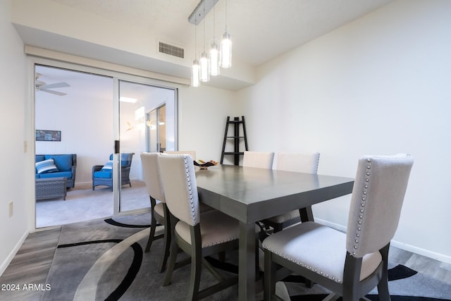 dining area featuring ceiling fan with notable chandelier and wood-type flooring