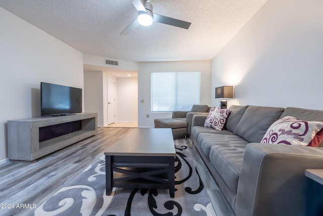 living room with a textured ceiling, light hardwood / wood-style flooring, and ceiling fan