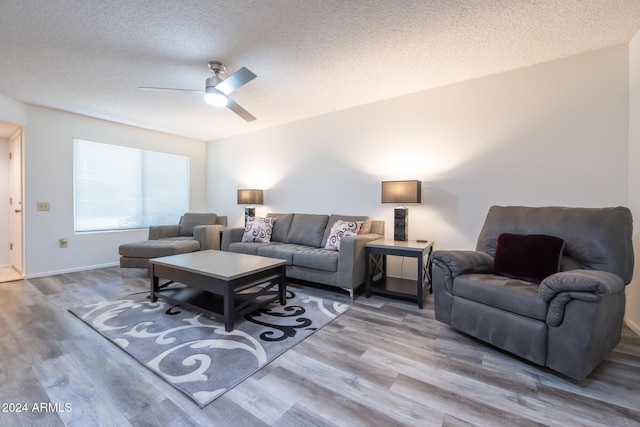 living room featuring hardwood / wood-style flooring, ceiling fan, and a textured ceiling