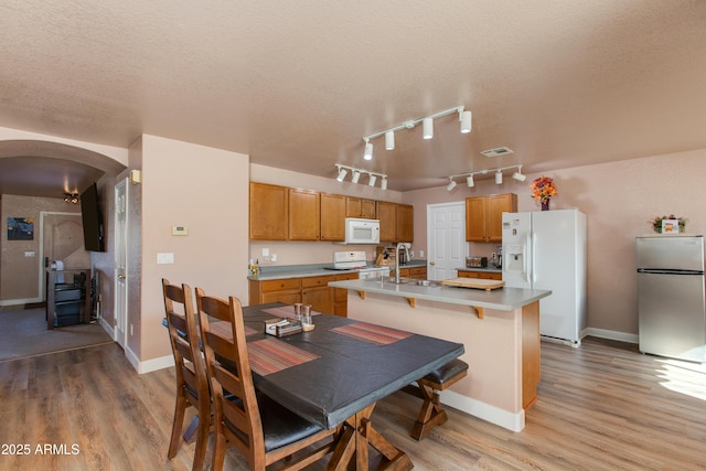 dining space with sink, a textured ceiling, and light hardwood / wood-style flooring