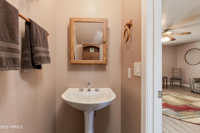 bathroom with ceiling fan and a textured ceiling