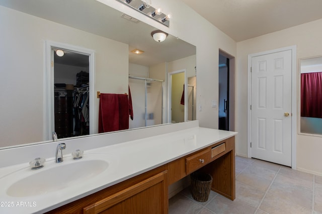 bathroom featuring tile patterned flooring, walk in shower, and vanity