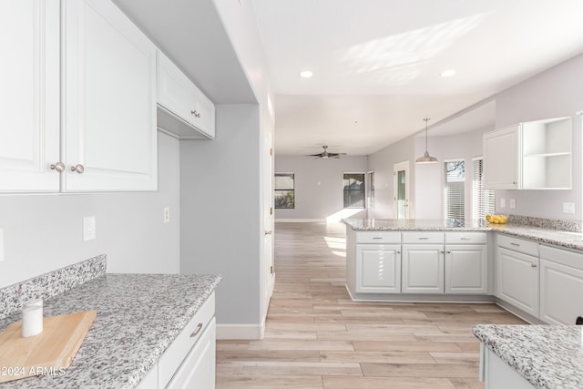 kitchen with white cabinetry, light stone counters, hanging light fixtures, kitchen peninsula, and ceiling fan