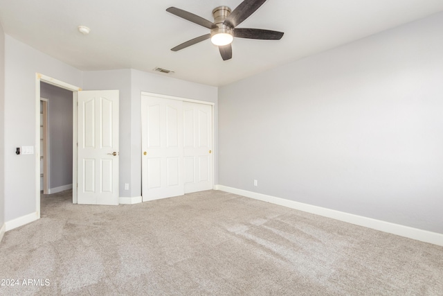 unfurnished bedroom featuring light colored carpet, ceiling fan, and a closet