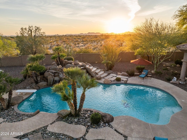 pool at dusk with a patio and a diving board