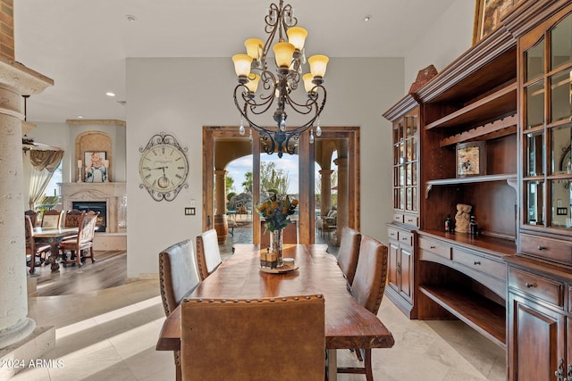 tiled dining room featuring ornate columns, a notable chandelier, and a premium fireplace