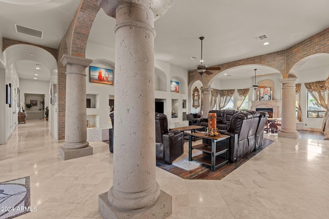 tiled living room featuring ceiling fan, built in features, and decorative columns