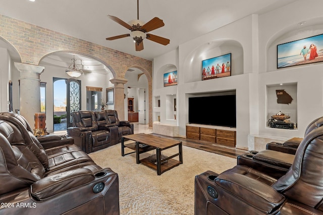 living room with wood-type flooring, decorative columns, built in features, brick wall, and ceiling fan