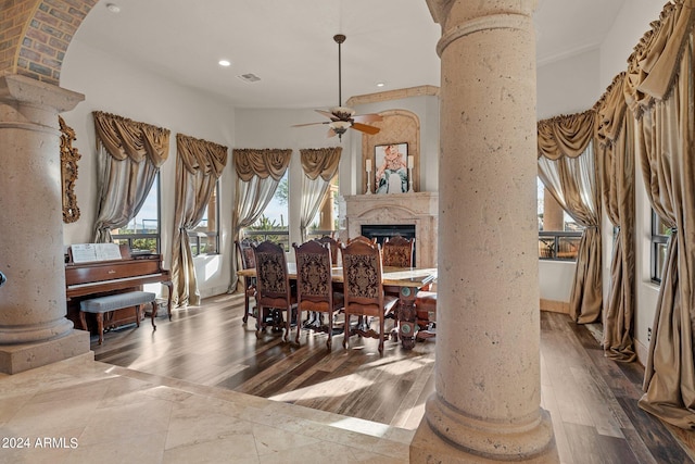 dining area featuring ceiling fan, decorative columns, a fireplace, hardwood / wood-style floors, and ornamental molding