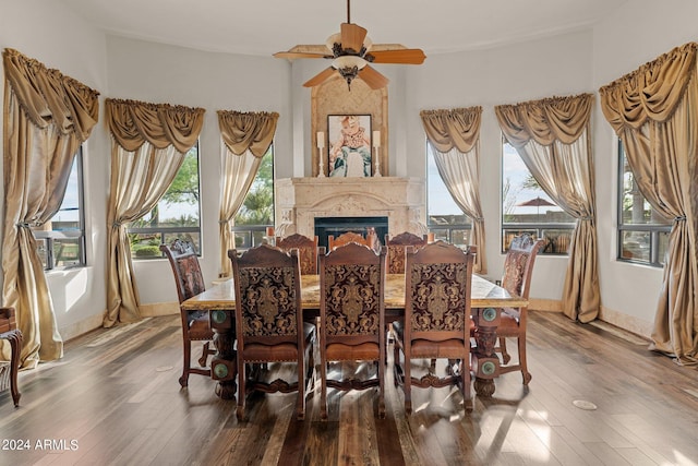 dining space featuring ceiling fan, hardwood / wood-style flooring, and a fireplace