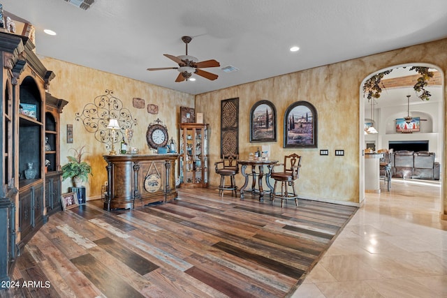 interior space featuring wood-type flooring, ceiling fan, wood walls, and built in shelves