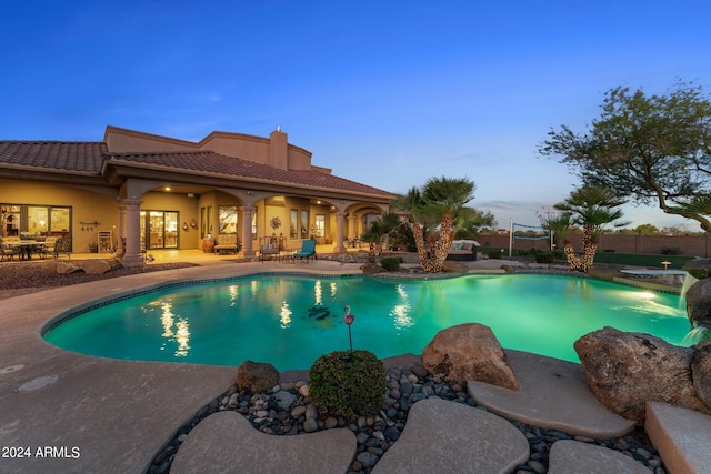 pool at dusk with a patio area