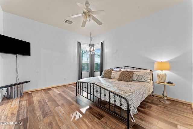 bedroom with hardwood / wood-style flooring and ceiling fan with notable chandelier