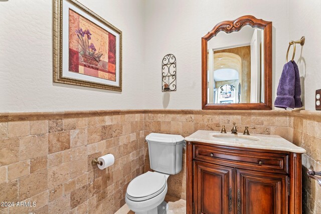 bathroom with vanity, tasteful backsplash, toilet, and tile walls