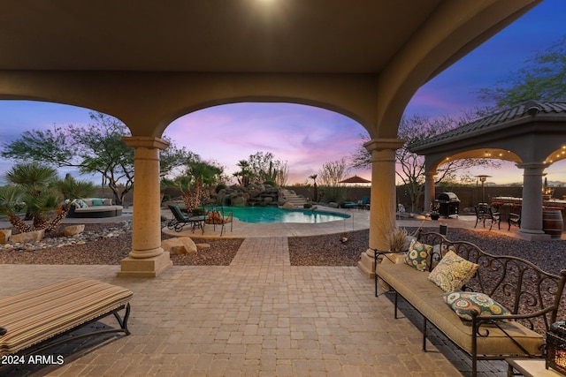 patio terrace at dusk featuring an outdoor hangout area, grilling area, a gazebo, and a fenced in pool