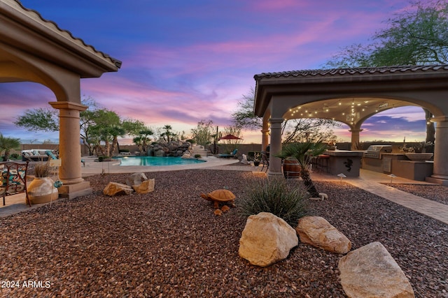 yard at dusk featuring a patio and an outdoor kitchen