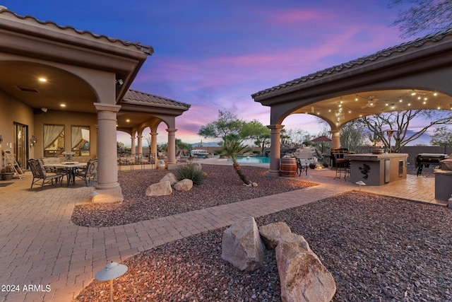 yard at dusk with a patio area, an outdoor bar, and area for grilling