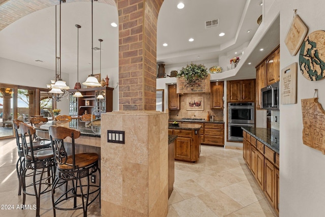 kitchen featuring a kitchen breakfast bar, pendant lighting, a kitchen island with sink, appliances with stainless steel finishes, and tasteful backsplash