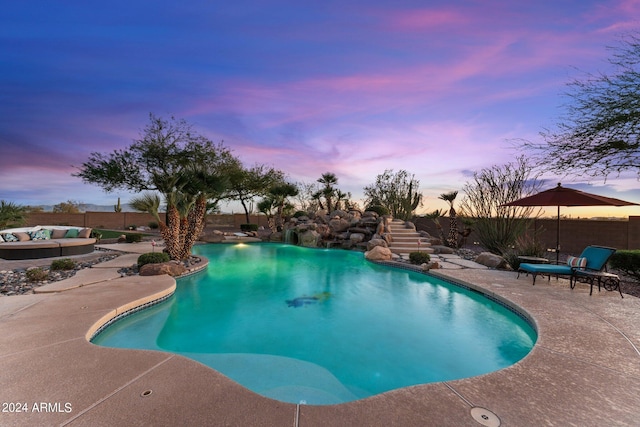 pool at dusk featuring a patio