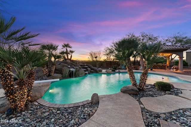 pool at dusk with a diving board and pool water feature