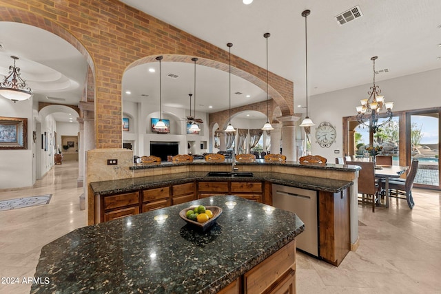 kitchen with hanging light fixtures, a spacious island, dark stone counters, and stainless steel dishwasher