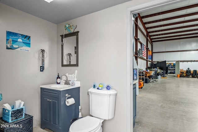 bathroom featuring concrete flooring, toilet, beam ceiling, and vanity