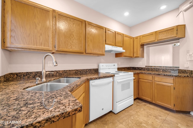 kitchen with dark stone countertops, white appliances, and sink