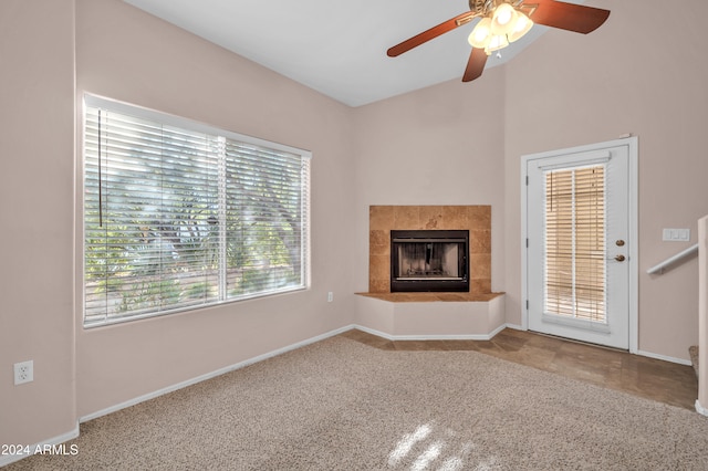 unfurnished living room with ceiling fan, a tiled fireplace, and carpet