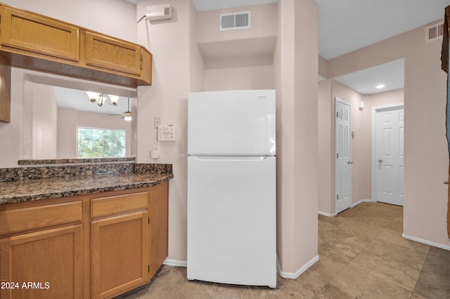 kitchen featuring dark stone counters, ceiling fan, and white fridge