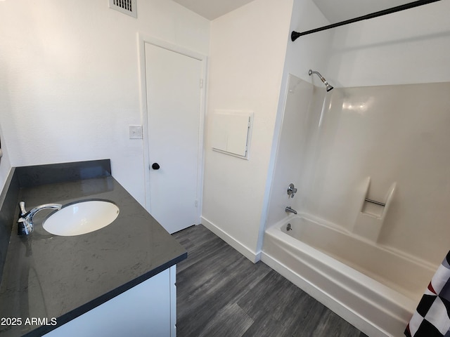 full bathroom featuring visible vents, baseboards, vanity, wood finished floors, and bathing tub / shower combination
