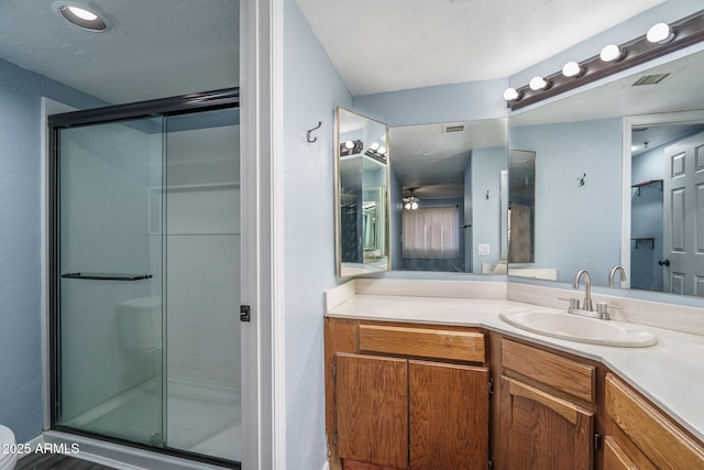 bathroom with vanity, ceiling fan, and a shower with door